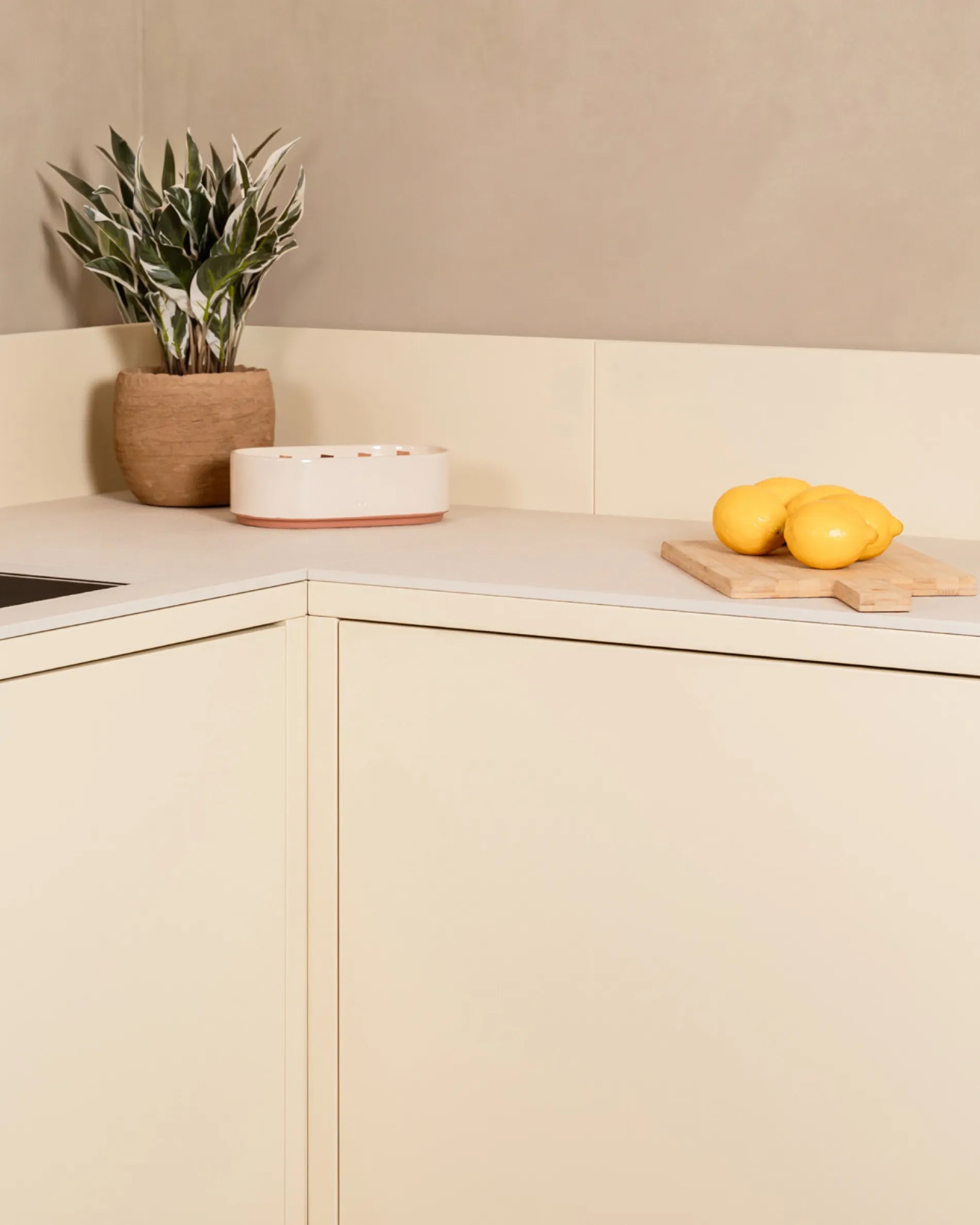 Hoekmodule PILOTIS in crèmebeige voor buitenkeukens, met plant en citroenen op het werkblad