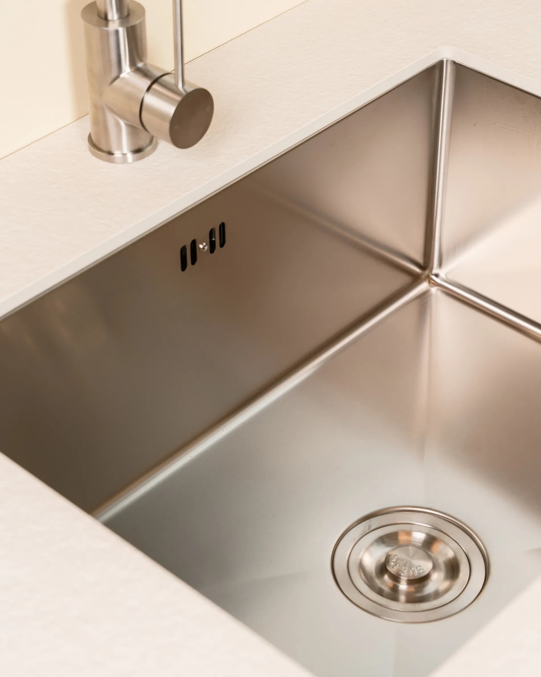 Inox wastafel van de PILOTIS Spoelmodule, verzonken in een beige-crèmekleurig werkblad, close-up