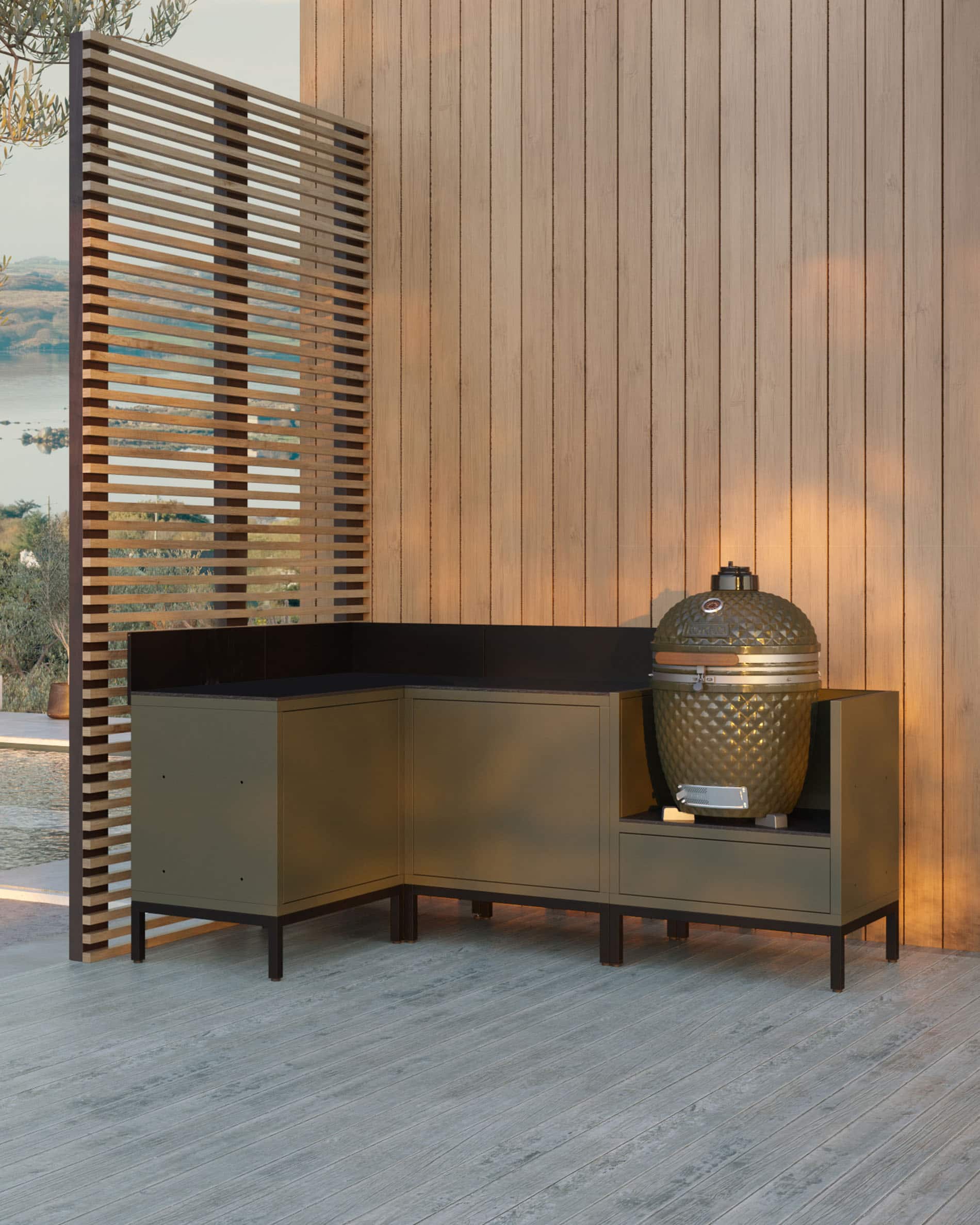 Hoekmodule voor buitenkeuken voor kamado, meubelset in olijfgroen met geïntegreerde spoelbak, donker werkblad en bijpassende achterwand, kamado geplaatst in het rechter zijmodule, constructie op zwarte poten.
