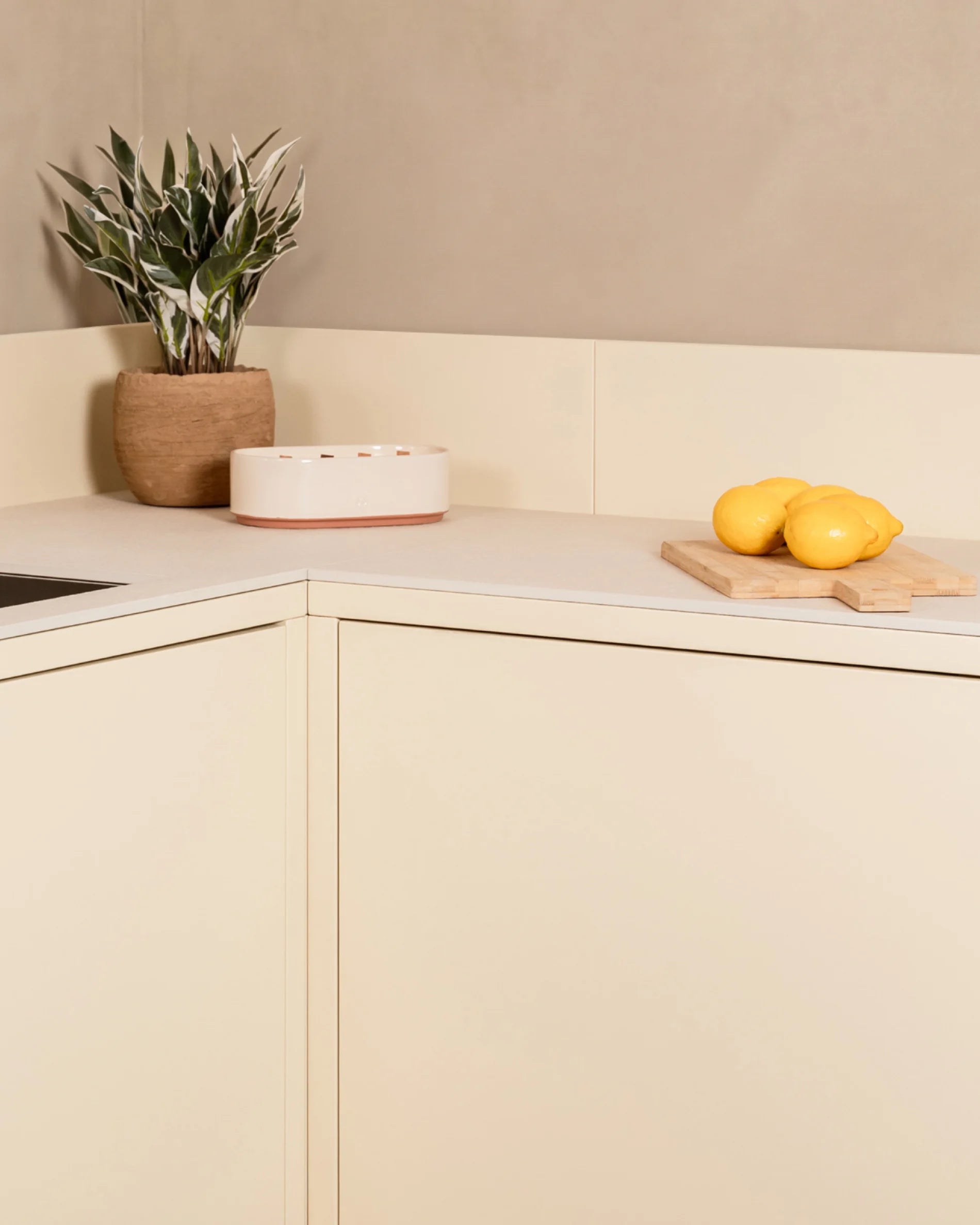 Detail van de hoek van de Kokko crème buitenkeuken met werkblad en plantendecoratie