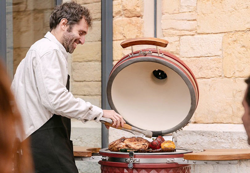 Kokko-expert demonstreert de beste grilltechnieken op een rode oxide kamado in de buitenlucht.