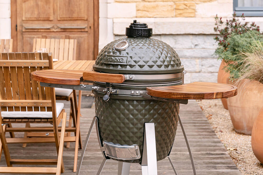 Kamado Kokko 18 inch in gebruik, met geopend deksel, luchtregeling en het gebruik van de barbecue in een realistische setting.