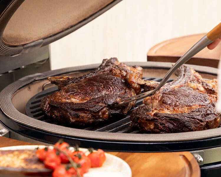 Direct grillen op de kamado Kokko XL 22 inch, met een illustratie van het dichtschroeien van ingrediënten op het roestvrijstalen rooster.