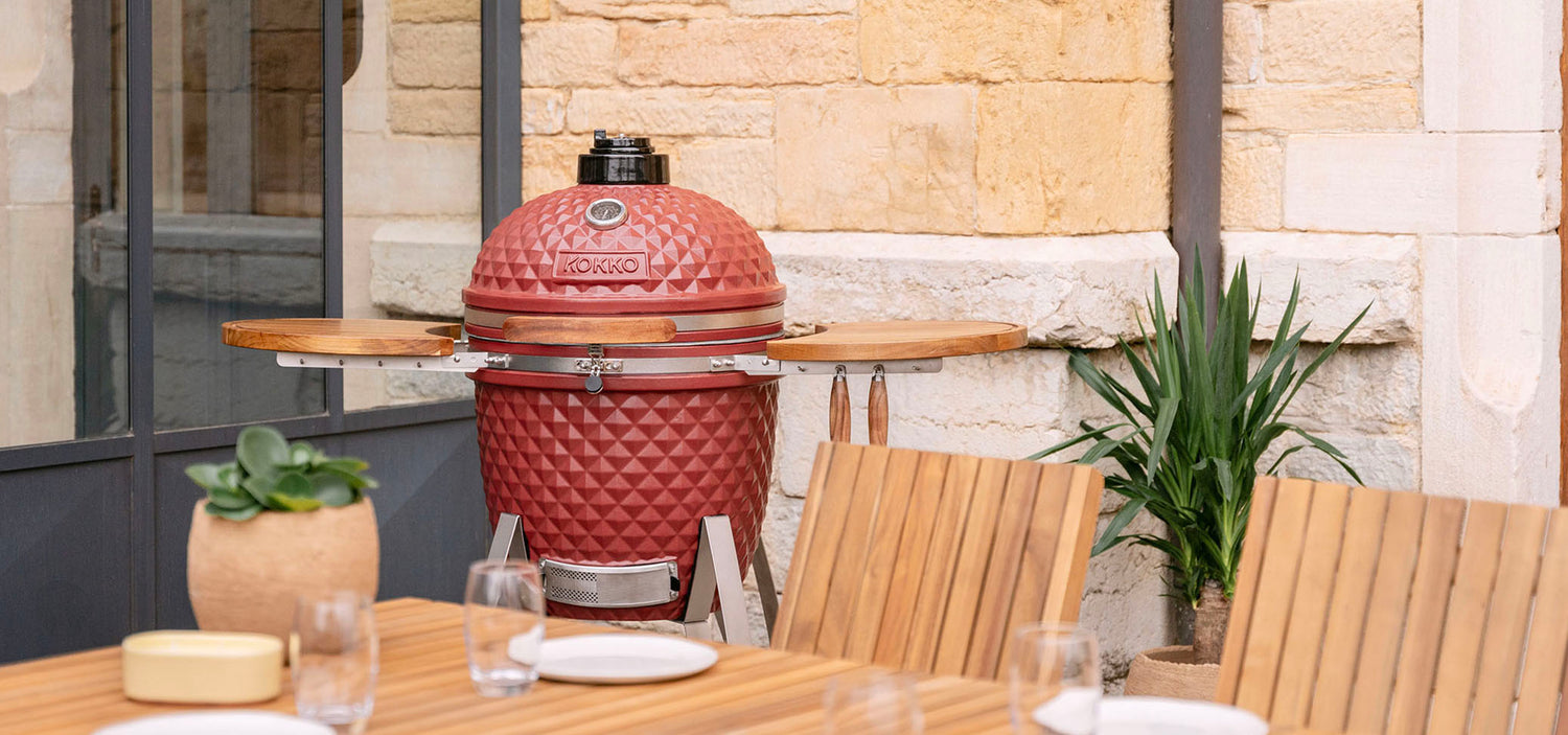 Kamado Kokko in oxide-rood geplaatst buiten, die de sfeer en het verhaal van het merk illustreert.