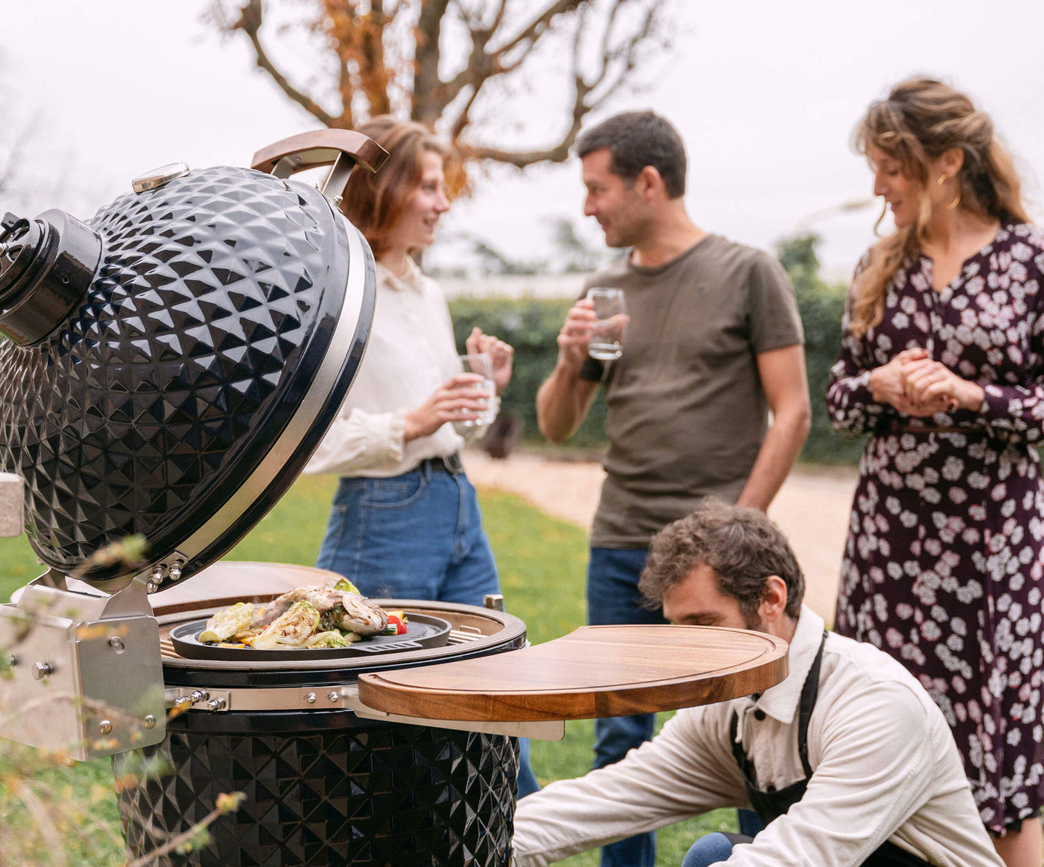Kamado Kokko nieuwe editie in gebruik, met etenswaren die aan het garen zijn om de gezelligheid en de prestaties van de barbecue te illustreren.