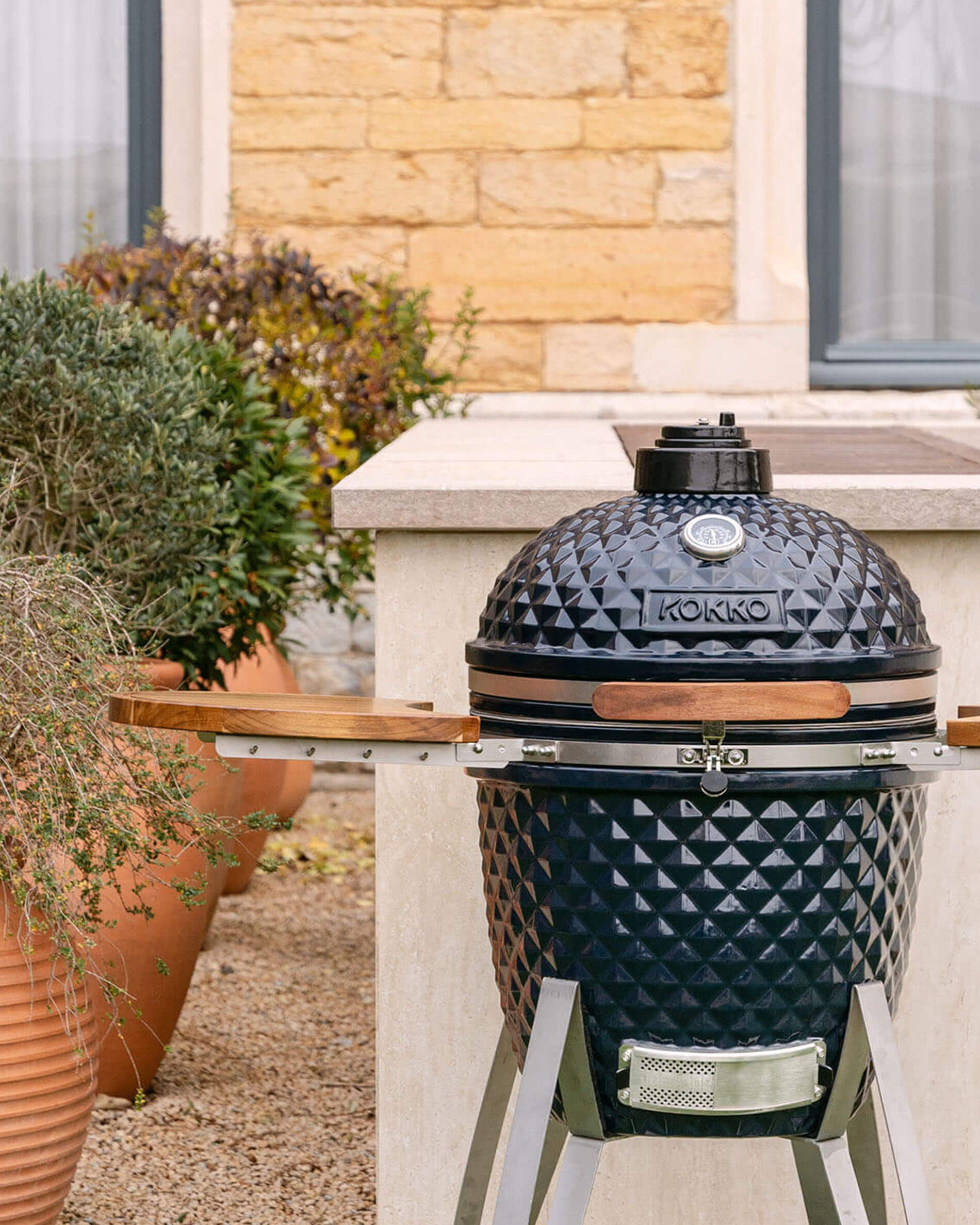 Kokko kamado-barbecue 22 inch in navy kleur, solo gepresenteerd in de buitenlucht.