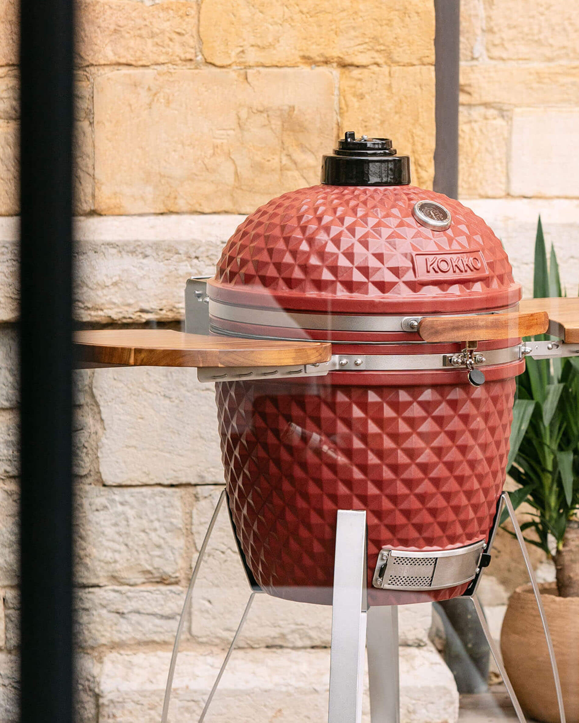 Kokko kamado-barbecue 22 inch in oxiderood, solo gepresenteerd in de buitenlucht.